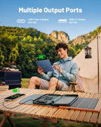 A young man sits outdoors by a tent, using his tablet and phone connected to the 30W Portable Foldable Solar Charger on a wooden table. The text highlights its multiple output ports—USB-C and USB-A—making it perfect for fast solar charging of phones, tablets, and power banks while camping.