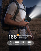 At dusk, a person outdoors shines a brilliant LED emergency flashlight powered by the 50000mAh Solar Power Bank – Magnetic Wireless Charger with Hand Crank, 4 Solar Panels & Built-In Charging Cables, lighting up the path ahead. On-screen text reads: “168 FT LED Emergency Flashlight” and “3 Modes: Standard, SOS, Strobe.”.