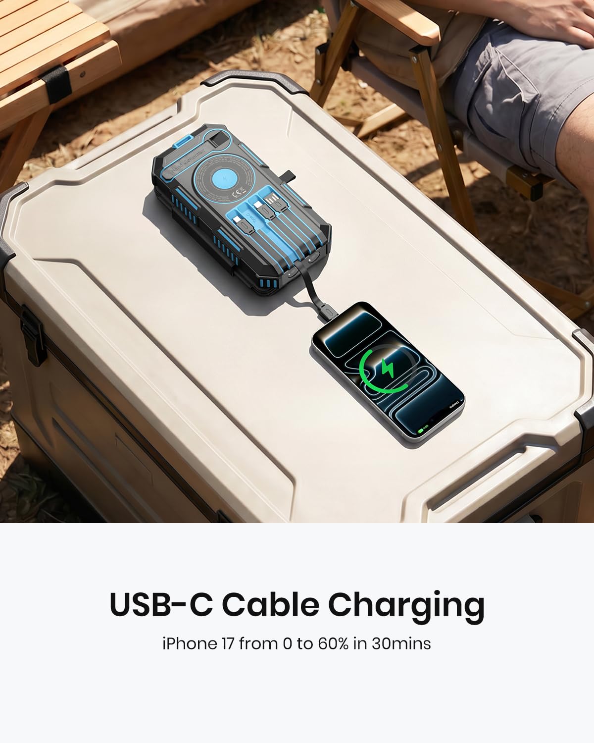 A person relaxes on a bench outdoors, effortlessly charging their iPhone 17 with the 50000mAh Solar Power Bank – Magnetic Wireless Charger featuring hand crank, four solar panels, and built-in charging cables. Text reads: "USB-C Cable Charging. iPhone 17 from 0 to 60% in 30mins." The power bank sits conveniently on a cooler nearby, showcasing its reliable emergency power capabilities.