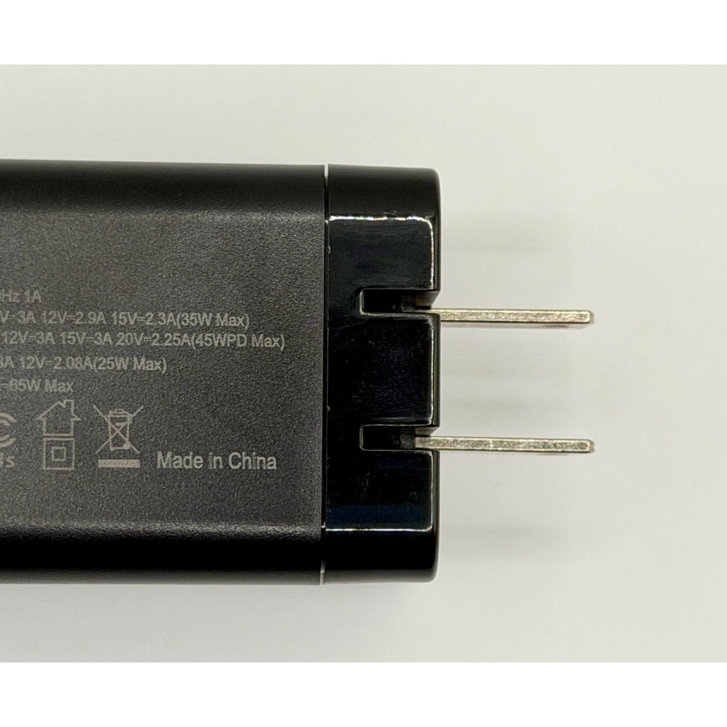 A close-up of the 65W GaN USB-C Wall Charger with Built-In Cable & Foldable Plug, featuring two metal prongs and technical specs on its surface, highlights its fast charging capability and "Made in China" text.
