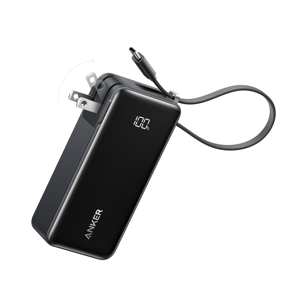 A black Anker Power Bank (10K, Fusion, Built-In Cable) with a digital display reading "100%" and a foldable wall plug. Its charging cable extends outward, all set against a plain white background.