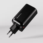 A black wall charger called The Fast Charger, with two round pins and a red indicator light, displays "the handy" in white on its side and is set against a plain light gray background.