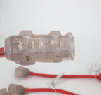 Close-up of a 30 Amp Generator Adapter Cord (L5-30P to 3x 5-15R Outlets) with a transparent rectangular connector on a red cable; more red cables and generator adapters are visible on a white surface in the background.