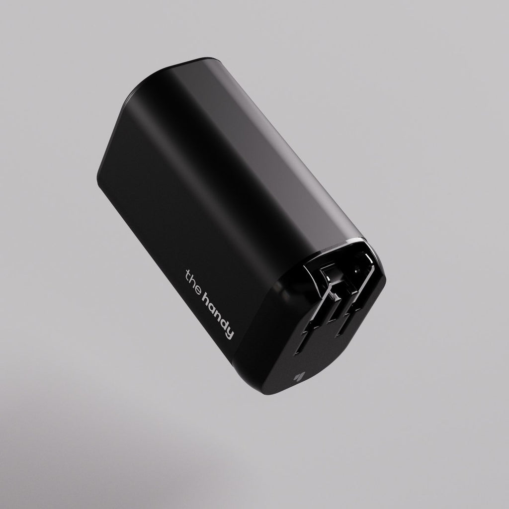 A black rectangular electronic device with two prongs, resembling a power adapter, labeled "The Fast Charger" on its side, set against a plain light gray background.