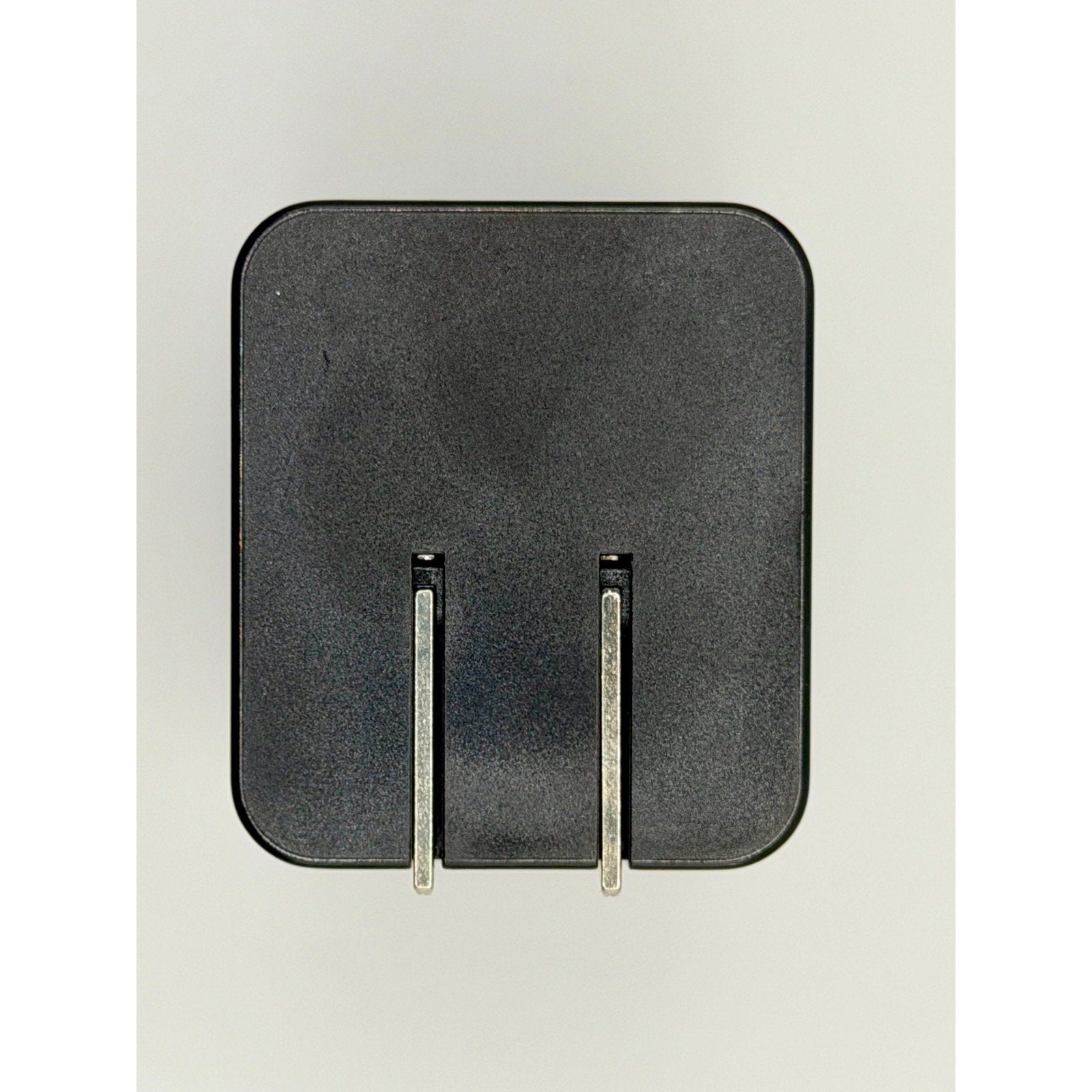 A black 65W GaN USB-C Wall Charger with a built-in cable and foldable plug is shown against a plain light background, featuring two metal prongs facing forward.
